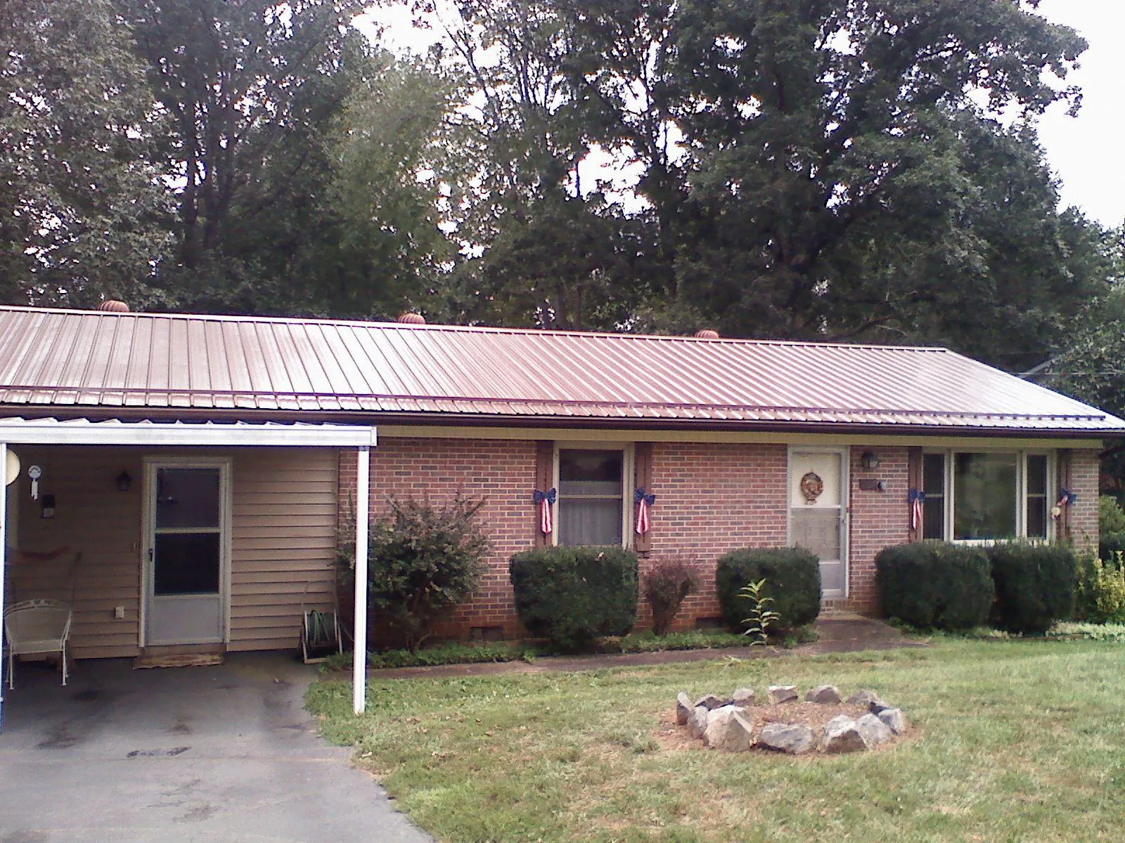 Bronze metal roof and carport on a brick ranch home — Roof Repair work by our crew in Manvel